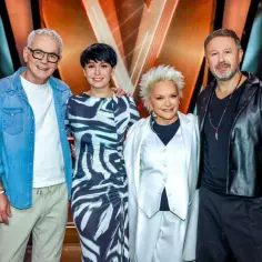 Czterech jurorów The Voice Senior, w tym Andrzej Piaseczny, w stylowych strojach, gotowi oceniać wokalne talenty.