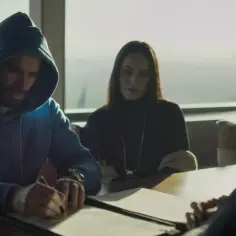 Mężczyzna w niebieskiej bluzie z kapturem podpisuje dokumenty. Obok siedzi kobieta, a z drugiej strony widać fragment twarzy kolejnej osoby. Czy to on wie, kto zabił Sarę?