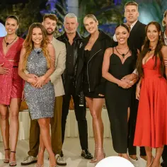 Uśmiechnięci uczestnicy Love Island 7 pozują do zdjęcia. Widać ich w eleganckich strojach, gotowych na kolejne wyzwania w willi.