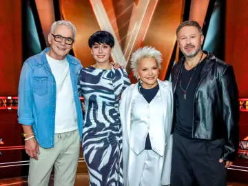 Czterech jurorów The Voice Senior, w tym Andrzej Piaseczny, w stylowych strojach, gotowi oceniać wokalne talenty.